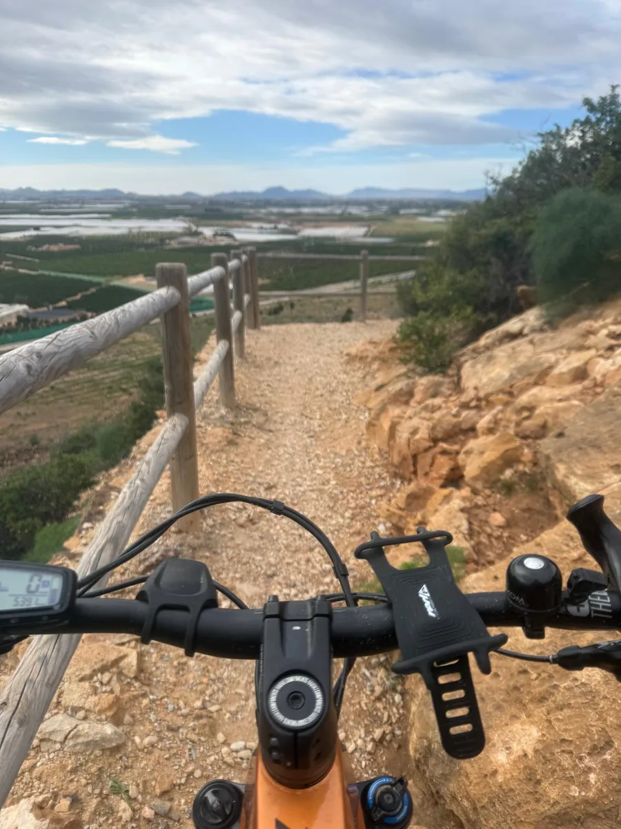 Vista desde el manillar de una bicicleta de montaña del camino con barandilla de madera y vistas sobre el Campo de Cartagena