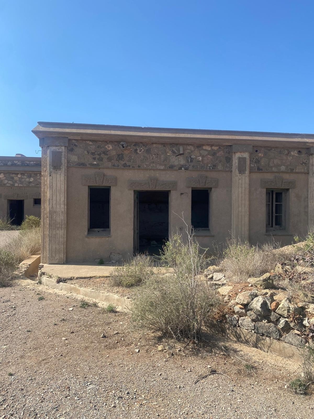 Abandoned barrack building with a natural stone upper course and decorated window surrounds at the coastal battery