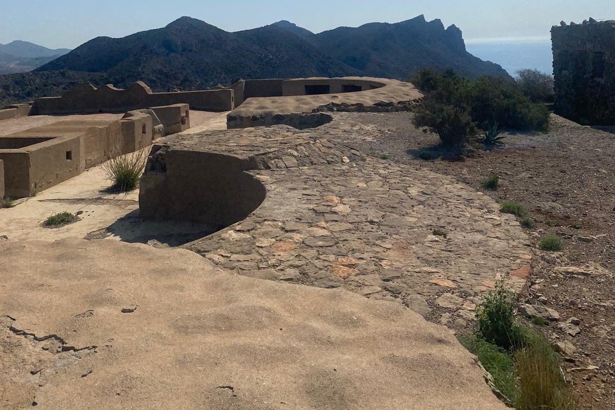 Concrete gun platform with circular emplacement and parapet, with the hills of the Sierra de la Fausilla behind