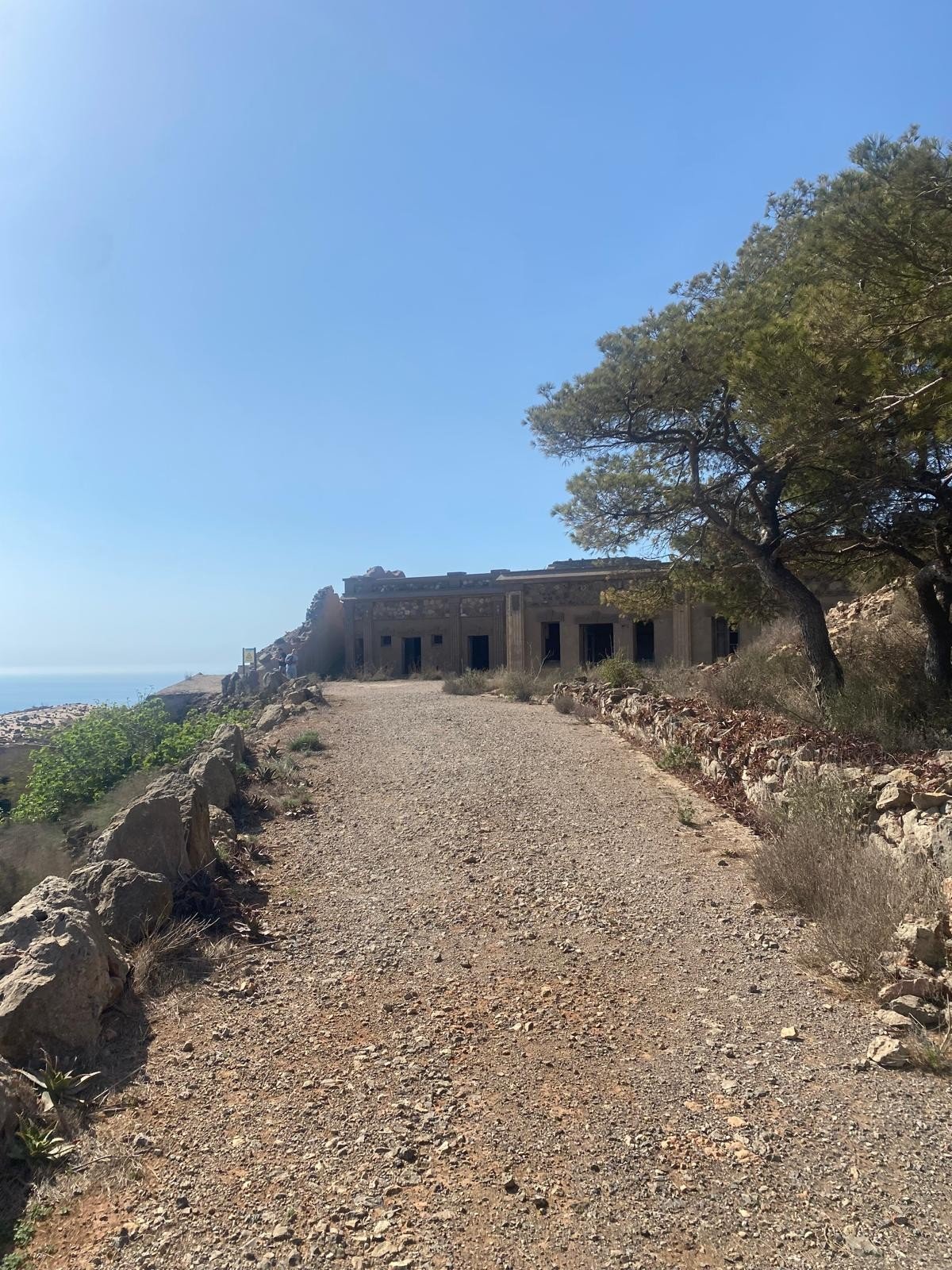 Broad track leading to a long barrack building on the ridge, with the sea to the left