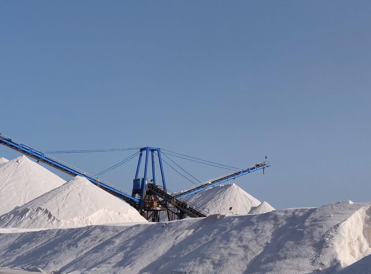 Monta&ntilde;as de sal blancas con cinta transportadora azul en la salina de San Pedro del Pinatar