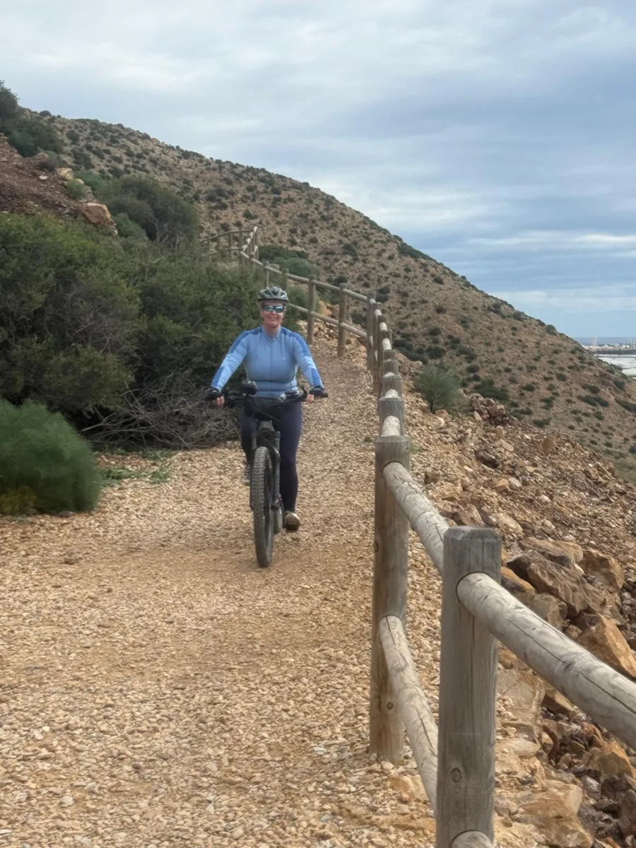 Ciclista de montaña en el camino de grava con barandilla de madera en la ladera del Cabezo Gordo