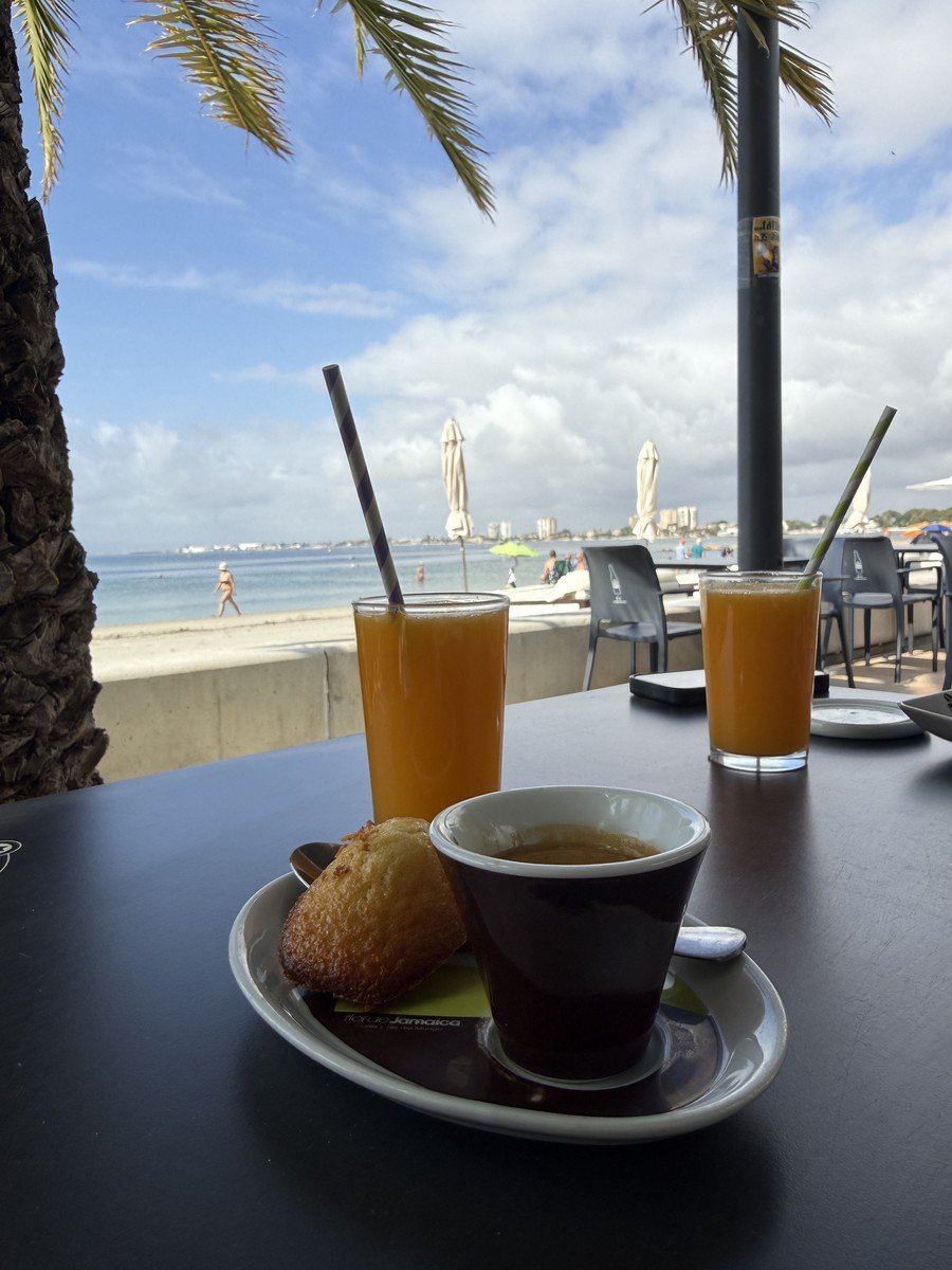 Desayuno espa&ntilde;ol con caf&eacute; y zumo de naranja natural en una terraza junto al mar