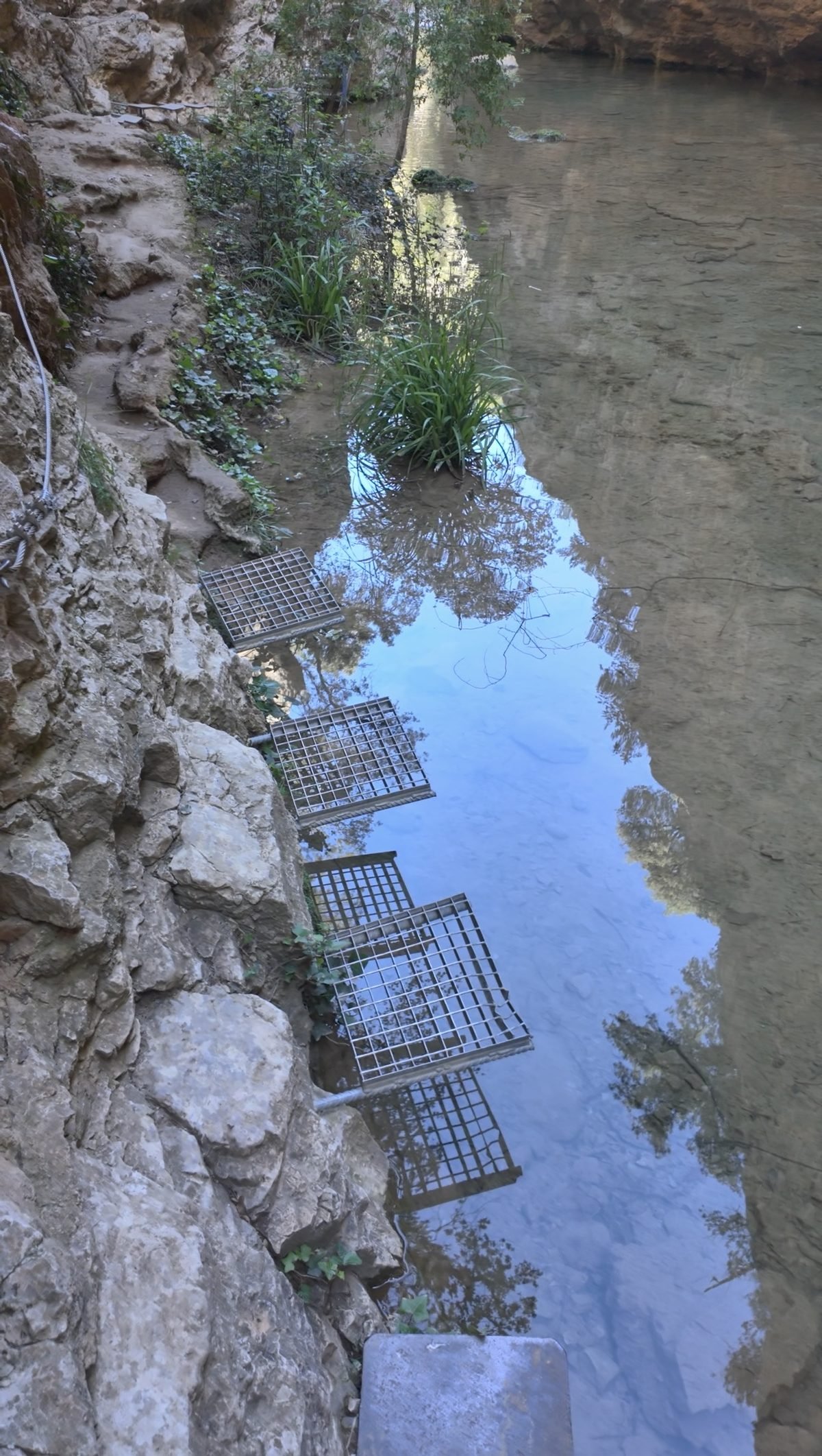 Metalen roostertrappen langs de rotswand naar het water