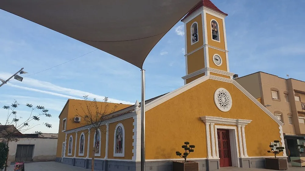 De gele kerkgevel en klokkentoren van Roldán