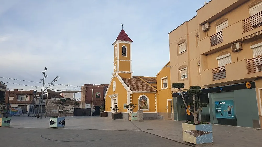 Het plein met de gele kerk en klokkentoren in Roldán