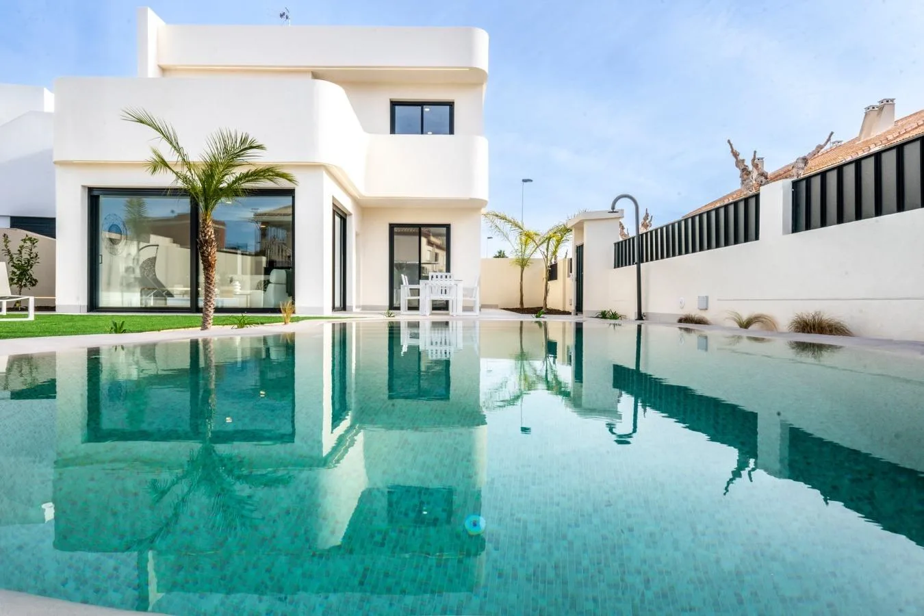 Een witte villa met terras, palmboom en privézwembad