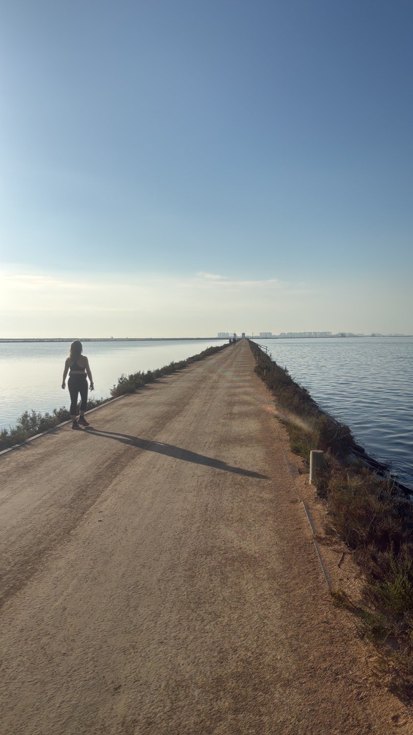 Senderista en el camino sobre el dique entre las salinas de San Pedro del Pinatar al amanecer