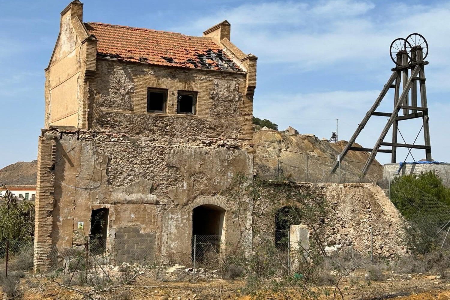 Maschinenhaus aus Ziegel und Putz mit einem h&ouml;lzernen F&ouml;rderturm daneben