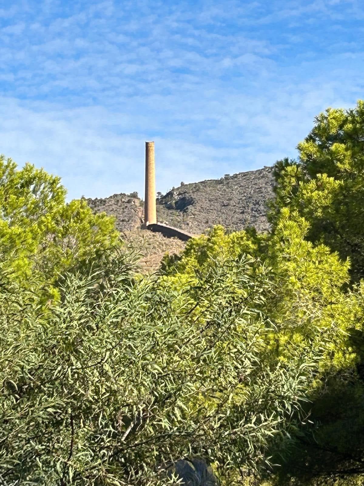 Freistehender Bergbauschornstein aus Ziegeln auf einem kahlen H&ouml;henzug der Sierra Minera