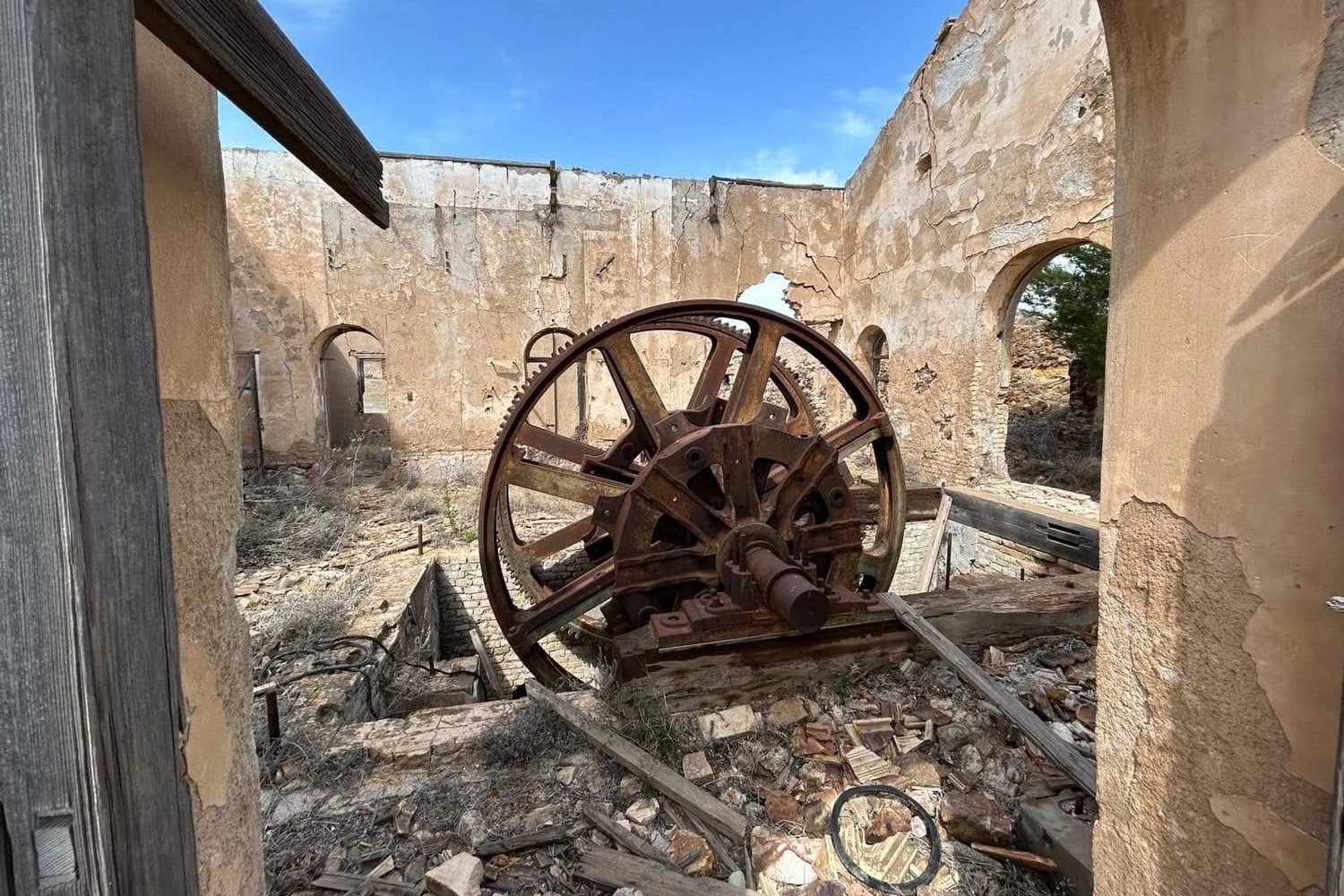 Gro&szlig;es verrostetes Zahnrad einer Bergbaumaschine in einer dachlosen Maschinenhalle