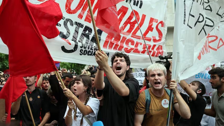 Spanische Demonstranten mit roten Fahnen und Transparenten protestieren gegen die Ablehnung der Wohnungsmaßnahmen