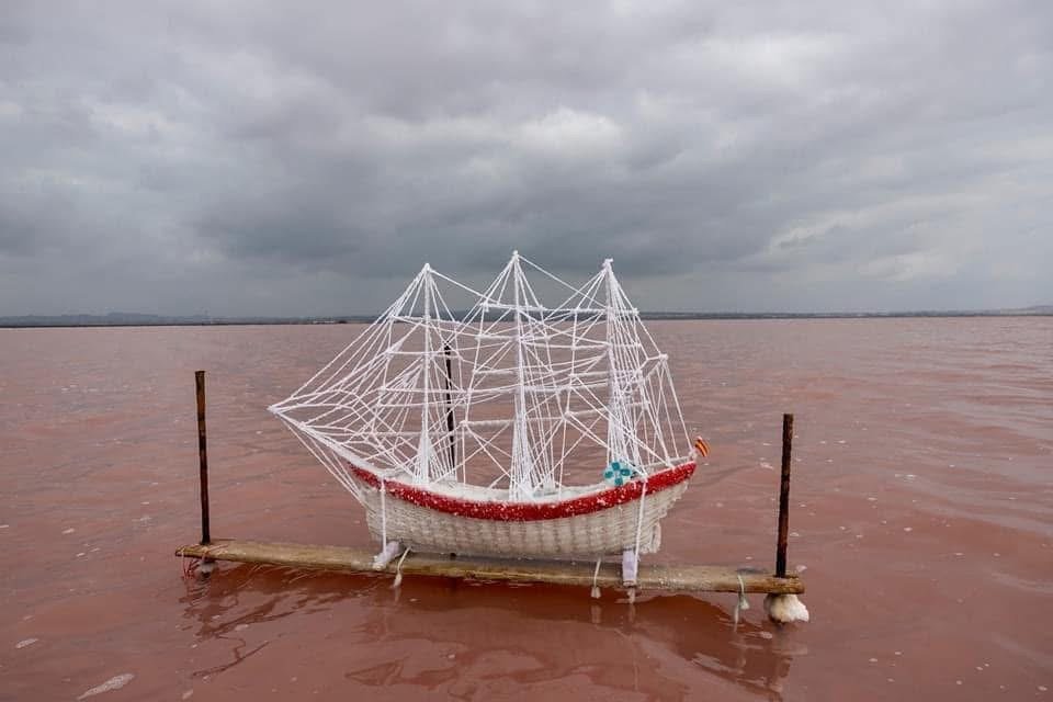 A salt-encrusted three-masted ship model on a jetty in the pink lagoon of Torrevieja